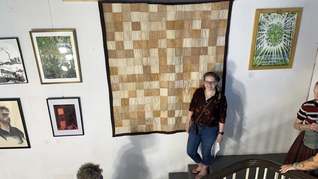 Brown quilt hanging in gallery